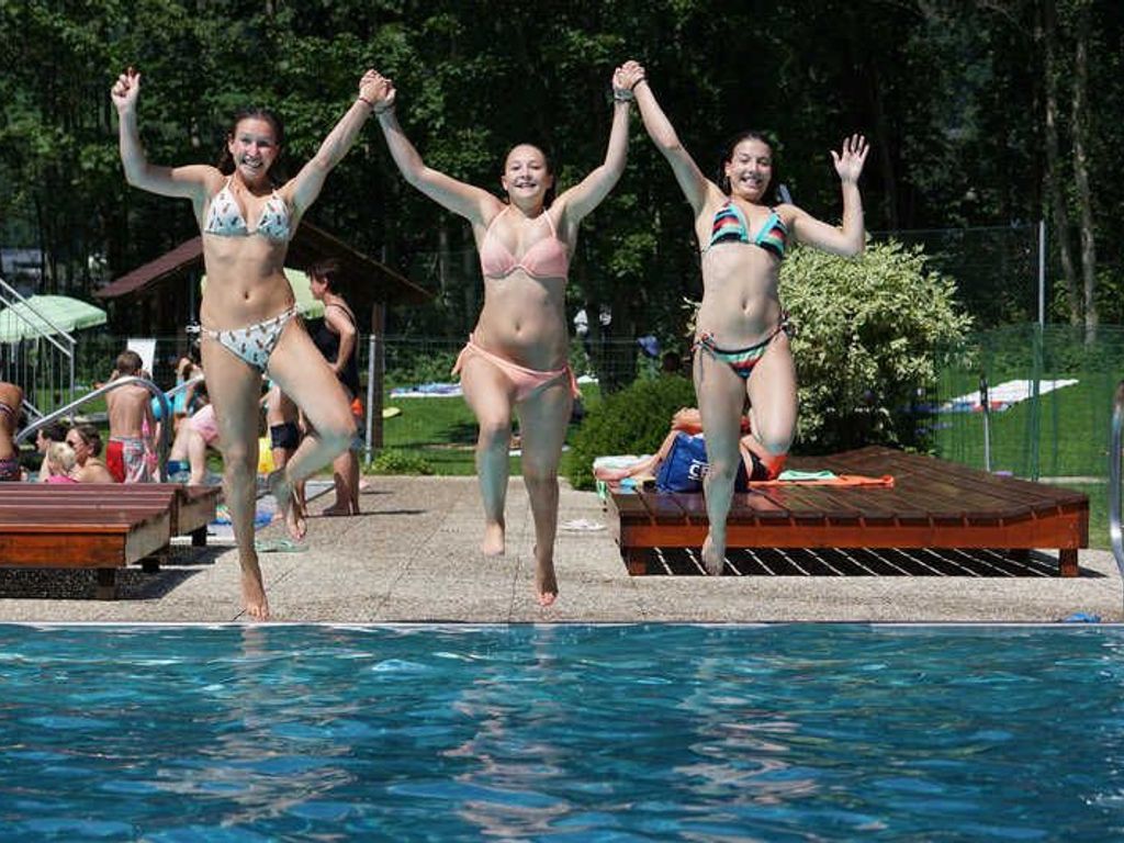 Una piscina con gente saltando al agua.