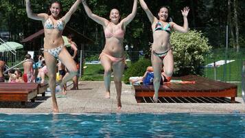 Una piscina con gente saltando al agua.