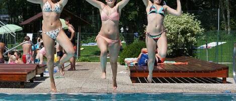 A swimming pool with people jumping into the water.