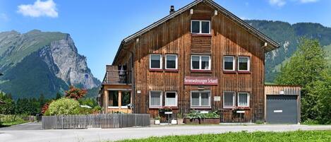 A wooden building with a sign reading 'Ferienwohnungen Schantl' in front of a mountain.