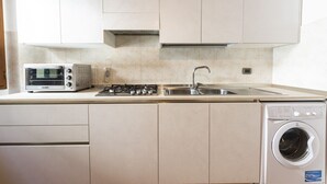A kitchen with a built-in microwave, gas stove, sink, and a front-loading washing machine. - San Frediano House, beautiful apartment in Via Romana by Mmega (Firenze)