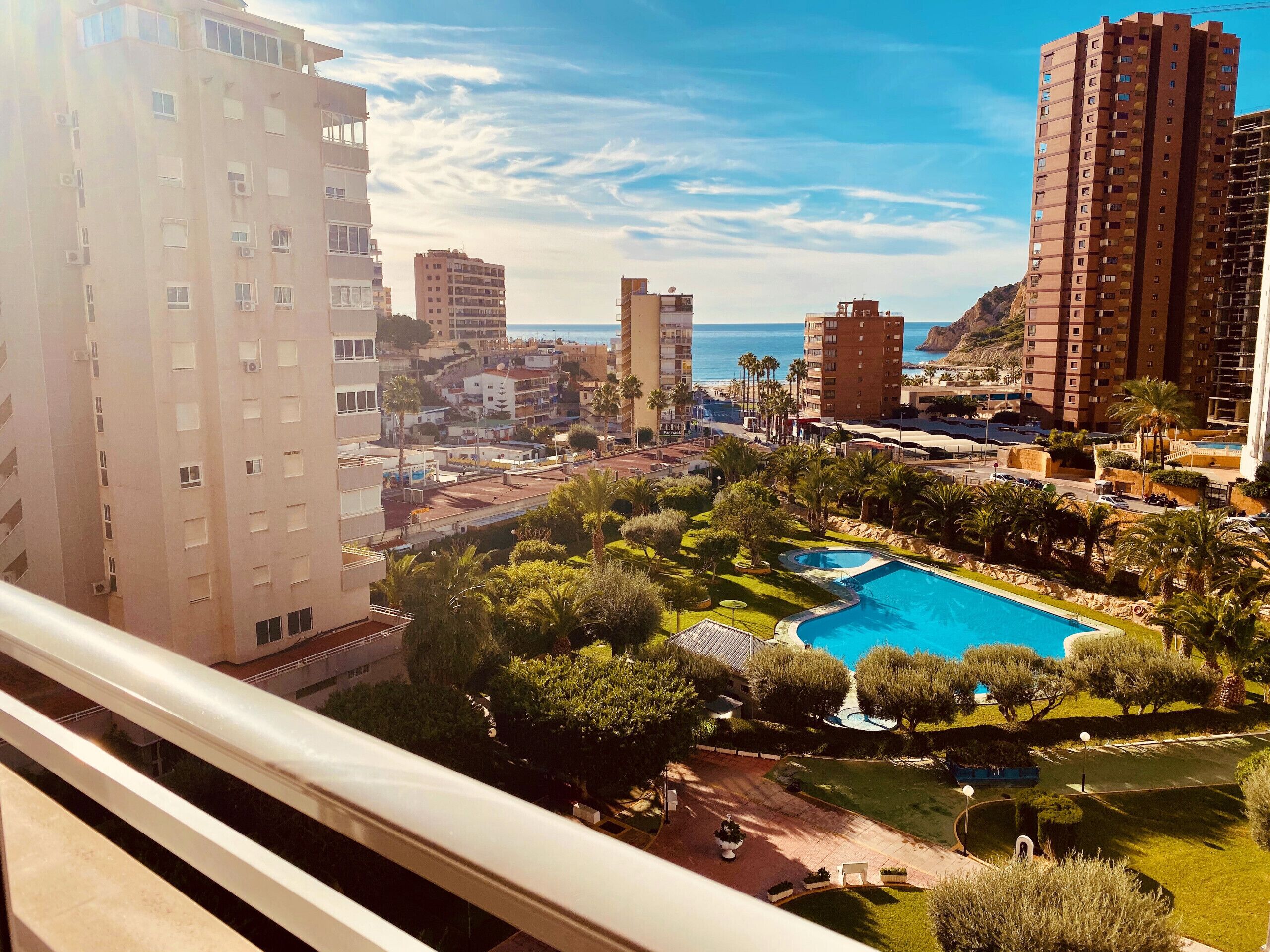 Un quartier résidentiel doté d’une piscine entourée de verdure, offrant une vue sur la mer et comprenant plusieurs immeubles de grande hauteur.