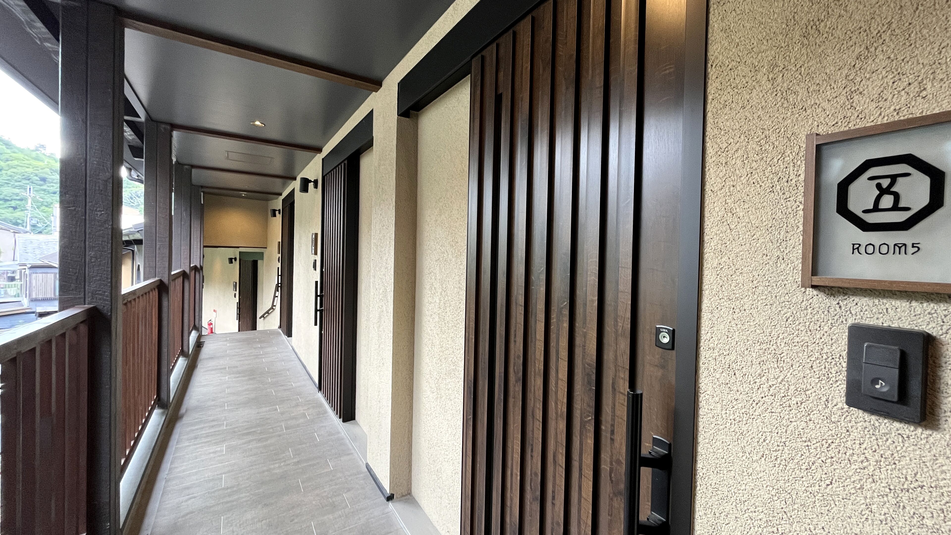 A hallway with wooden doors, a carpeted floor, and a sign indicating 'ROOM 5'.