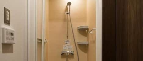 A small, enclosed shower area with a control panel and a handheld showerhead.