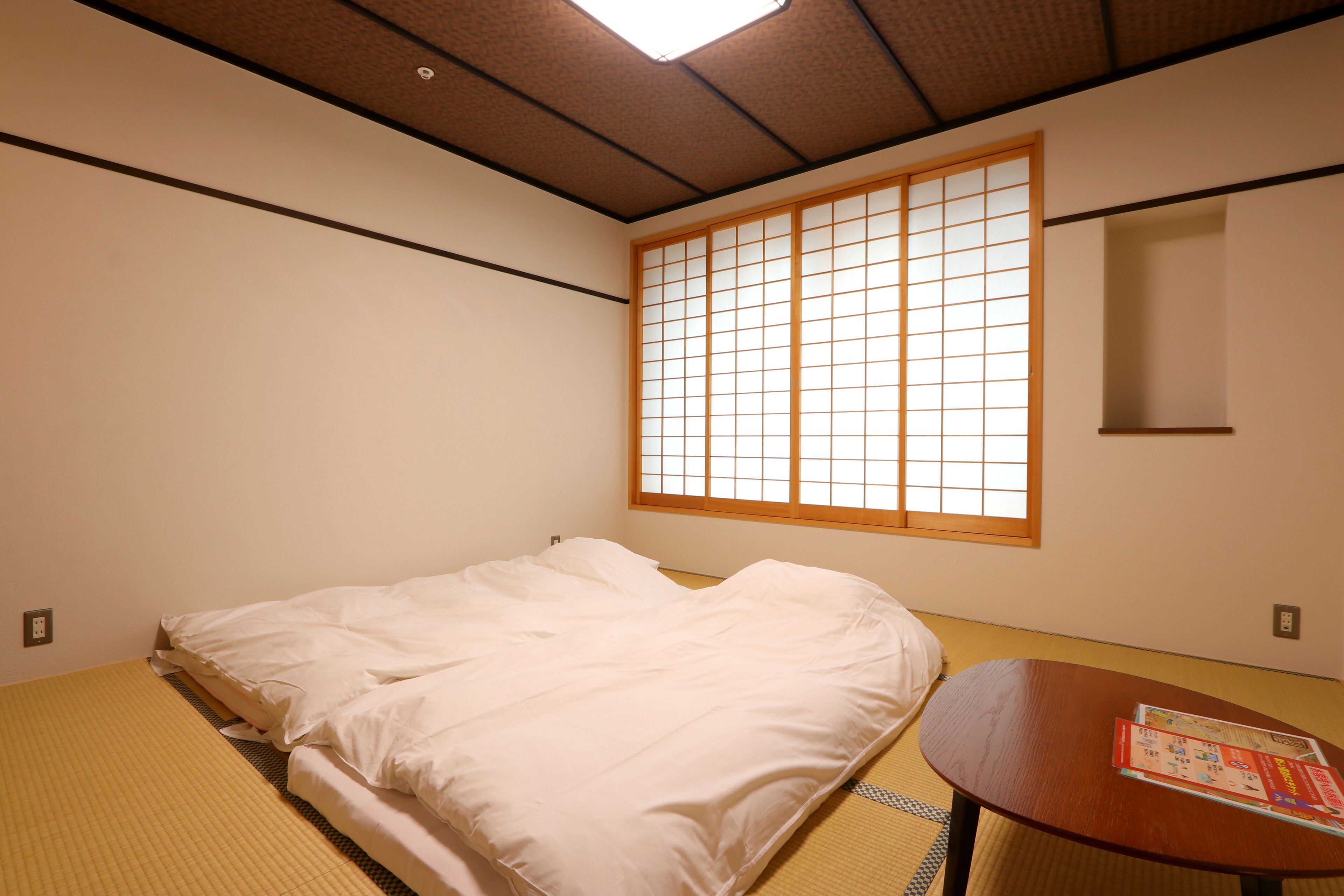 Una habitación con una cama, una mesita y un ventanal con diseño de cuadrícula.