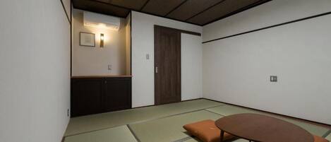 Um quarto japonês tradicional com tatames, uma mesa baixa, almofadas e um futum.