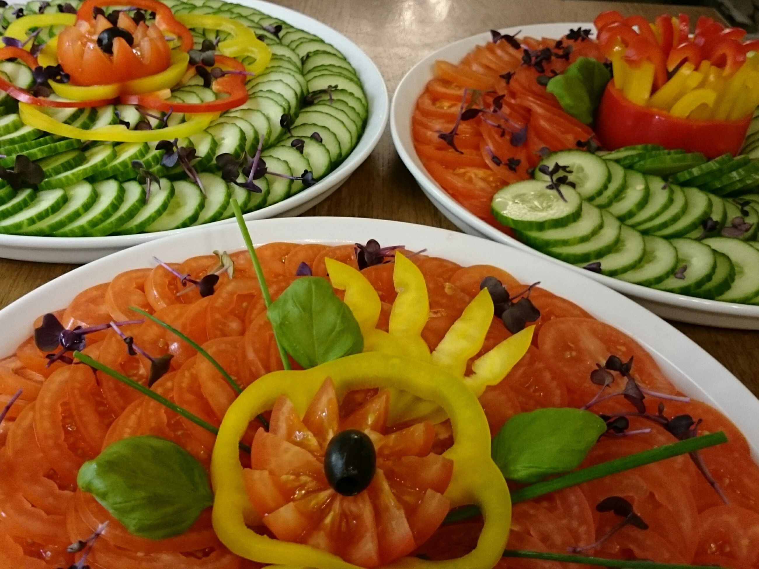 Drei Teller mit Essen, darunter verschiedene Gemüsesorten und Lachs.