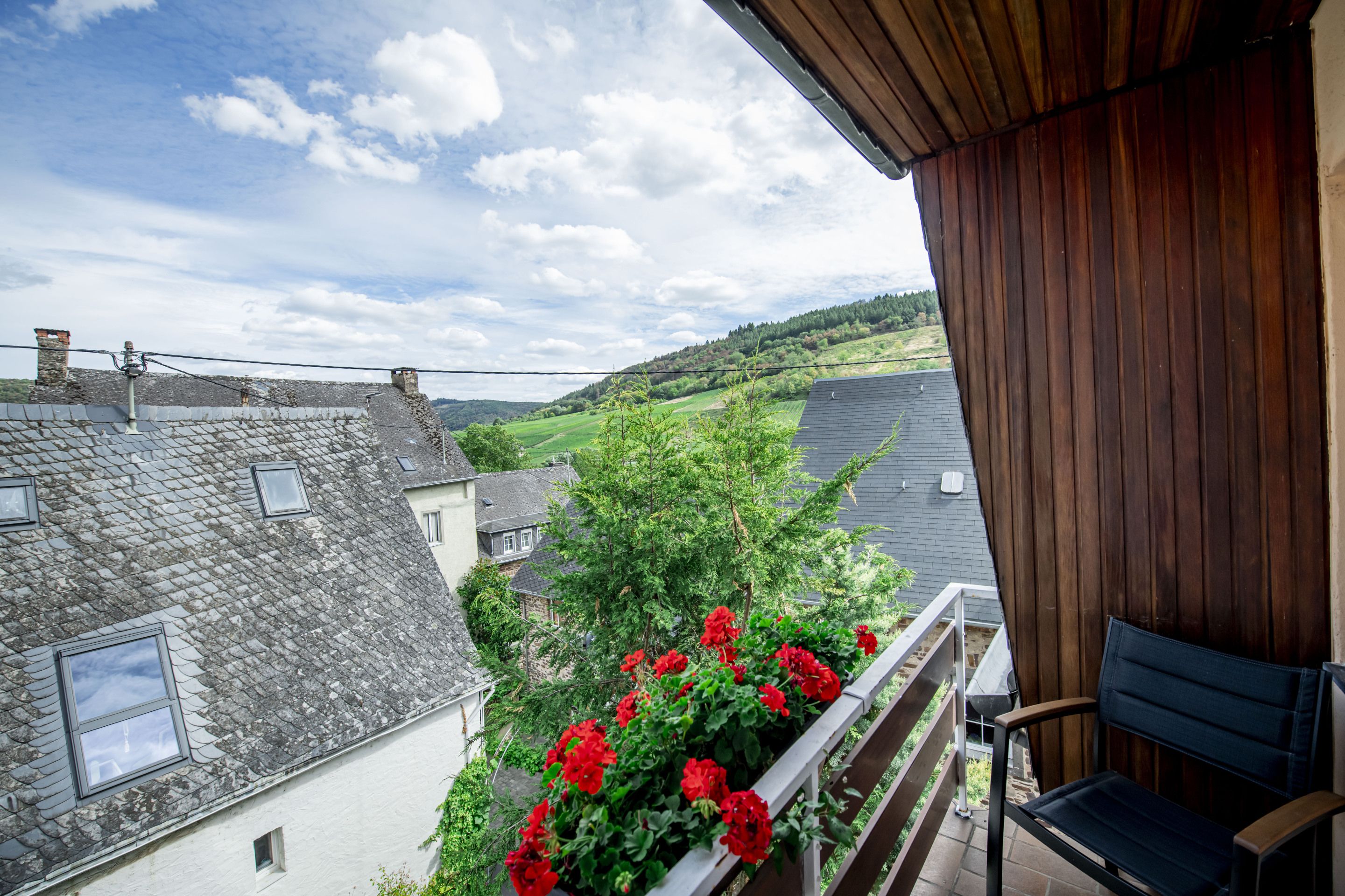 Ein Balkon mit Blick auf ein Dorf, einem Holgitter und einem Stuhl.