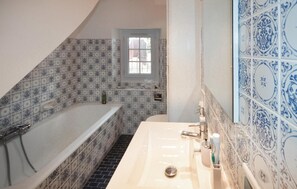 Ein Badezimmer mit Badewanne, Waschbecken und einem Fenster.