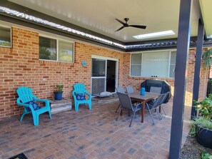 Ein Patio mit Backsteinmauern, einem Deckenventilator und einem Tisch mit Stühlen.