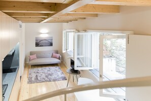 A modern interior with a sofa, TV, and a window with open shutters.