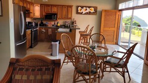Una cocina moderna con armarios de madera, electrodomésticos de acero inoxidable y una zona de comedor con sillas de mimbre y una mesa de vidrio.