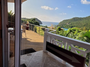Enjoy the serene view from this balcony overlooking a lush landscape and a body of water.