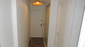 A narrow hallway with wooden flooring, white walls, and a door at the end.