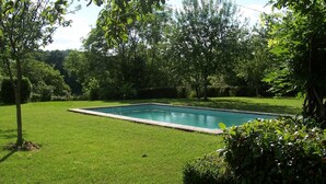 A rectangular swimming pool surrounded by well-maintained grass and trees. - 18th C House, Own Pool, Mountain, River Views, peaceful and private. (Pyrenees Atlantiques, Pays Basque)