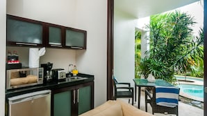 A compact kitchen with a microwave, toaster, and coffee maker, a small refrigerator, and a dining area with a table and chairs. - Mak Nuk Village-Studio-Swimup (Tulum)