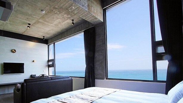 Een moderne hotelkamer met een groot bed, een flatscreen-tv, een bureau en uitzicht op de oceaan.