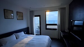 Een hotelkamer met een bed, een bureau en een raam met uitzicht op zee.