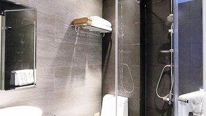 Een moderne badkamer met een glazen douchecabine, een wit toilet en een grote spiegel.