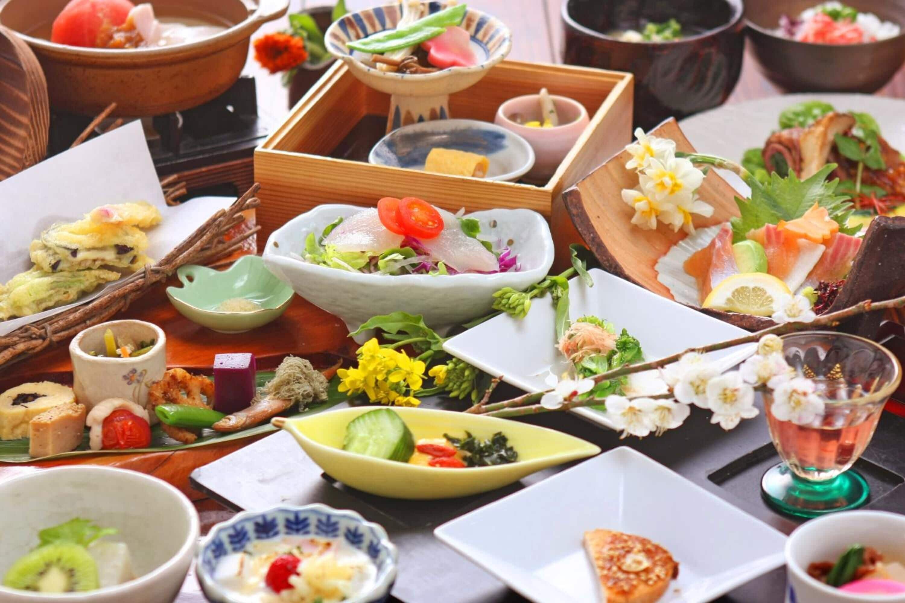 Eine Auswahl japanischer Gerichte auf einem Tisch, darunter Sushi, Sashimi und weitere kleine Speisen.