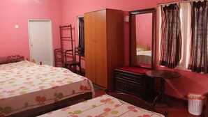 A bedroom with two beds, a wardrobe, a mirror, and a small table.
