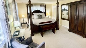 Ein Schlafzimmer mit Himmelbett, Nachttisch mit Lampe, Stuhl und Kleiderschrank.