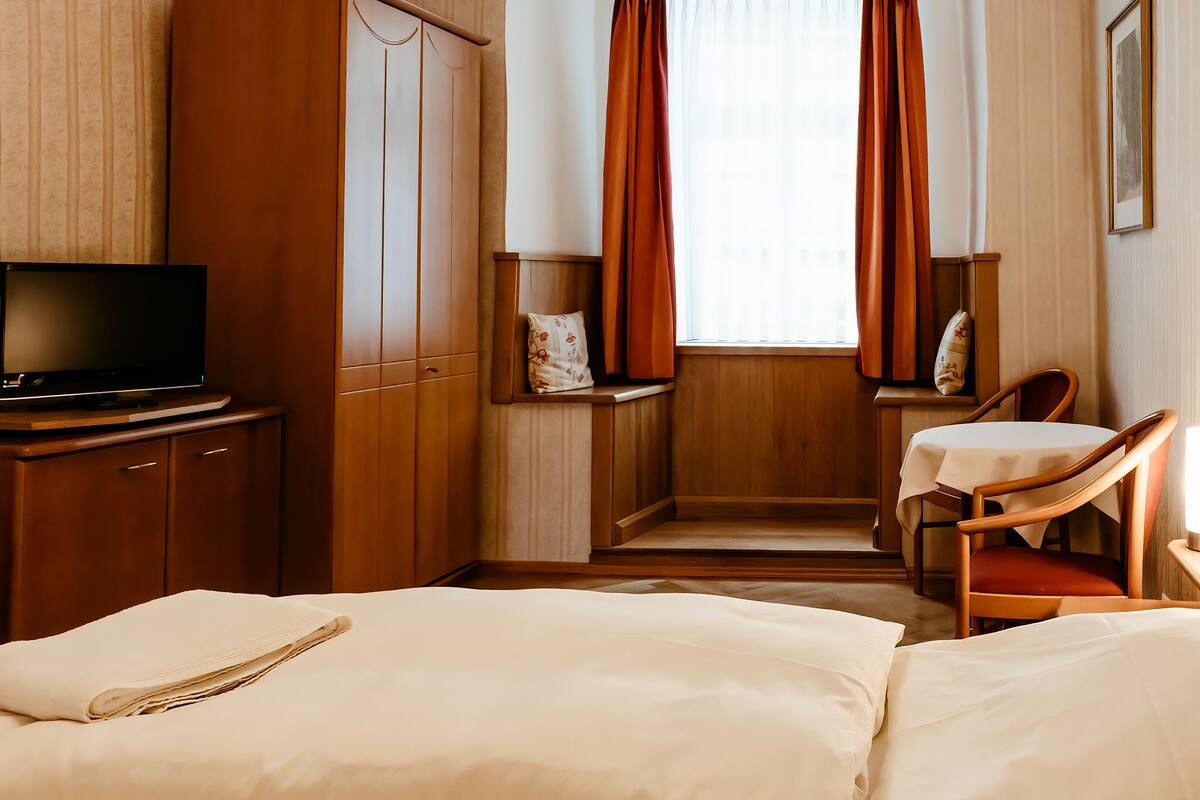 Une chambre d’hôtel avec un lit, une télévision, un bureau et une chaise.