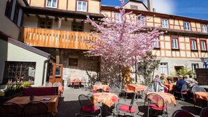 An outdoor café with tables and chairs, surrounded by traditional buildings with balconies and windows. - Hotel-Gasthof Goldener Greifen (Rothenburg ob der Tauber)