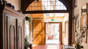 A hallway with a wooden door, a potted plant, and a table with a vase. - Hotel-Gasthof Goldener Greifen (Rothenburg ob der Tauber)
