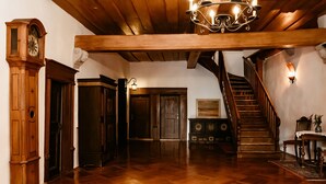 A spacious room with a wooden floor, a grandfather clock, a staircase, and a chandelier. - Hotel-Gasthof Goldener Greifen (Rothenburg ob der Tauber)
