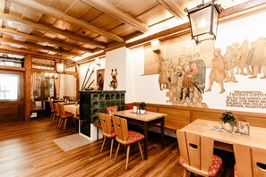 A restaurant interior with wooden floors, a dining area with tables and chairs, a fireplace, and a mural on the wall.