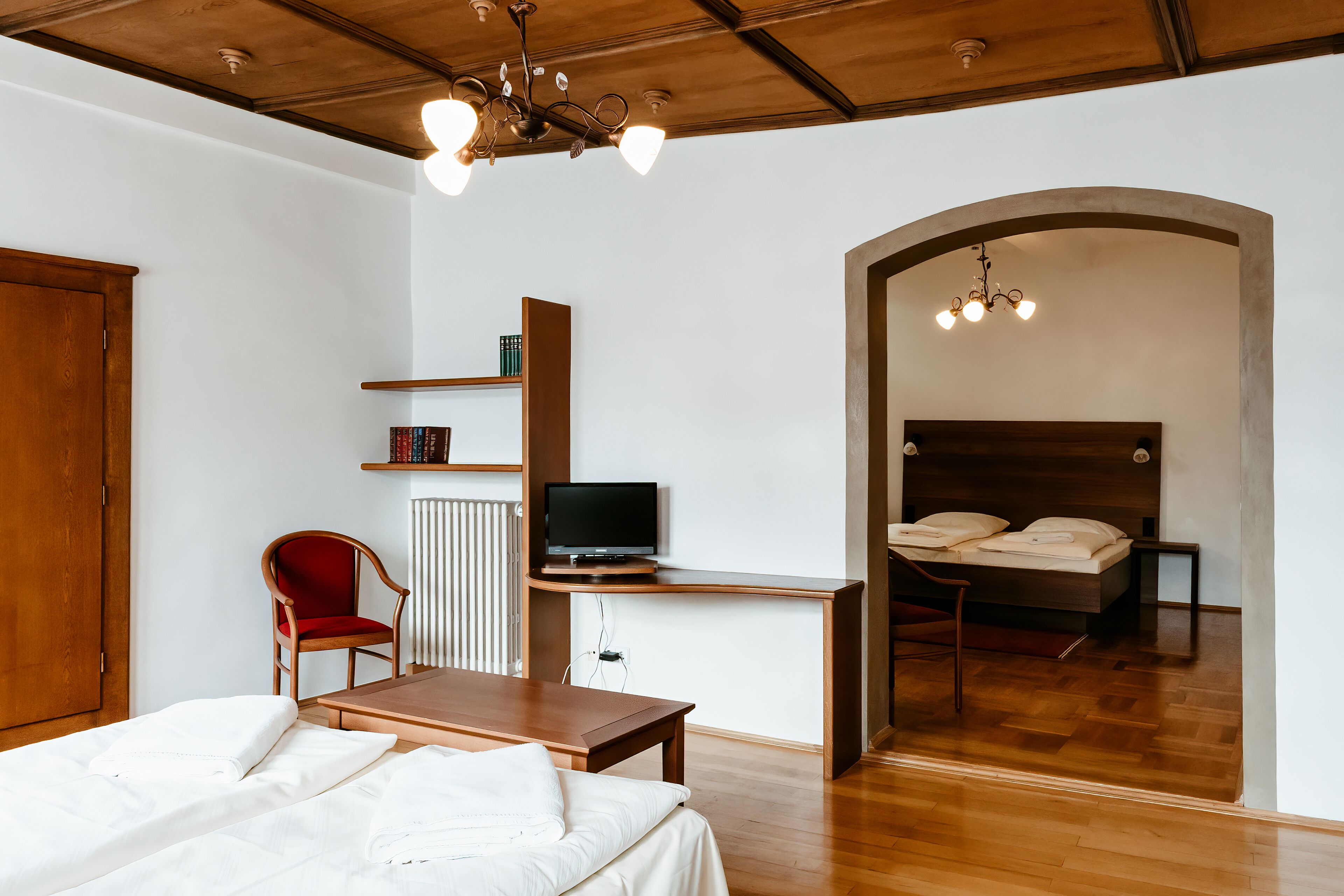 Un dormitorio con una cama, un escritorio con televisor, una silla y una estantería.