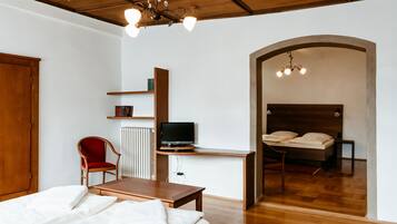 A bedroom with a bed, a desk with a TV, a chair, and a bookshelf.