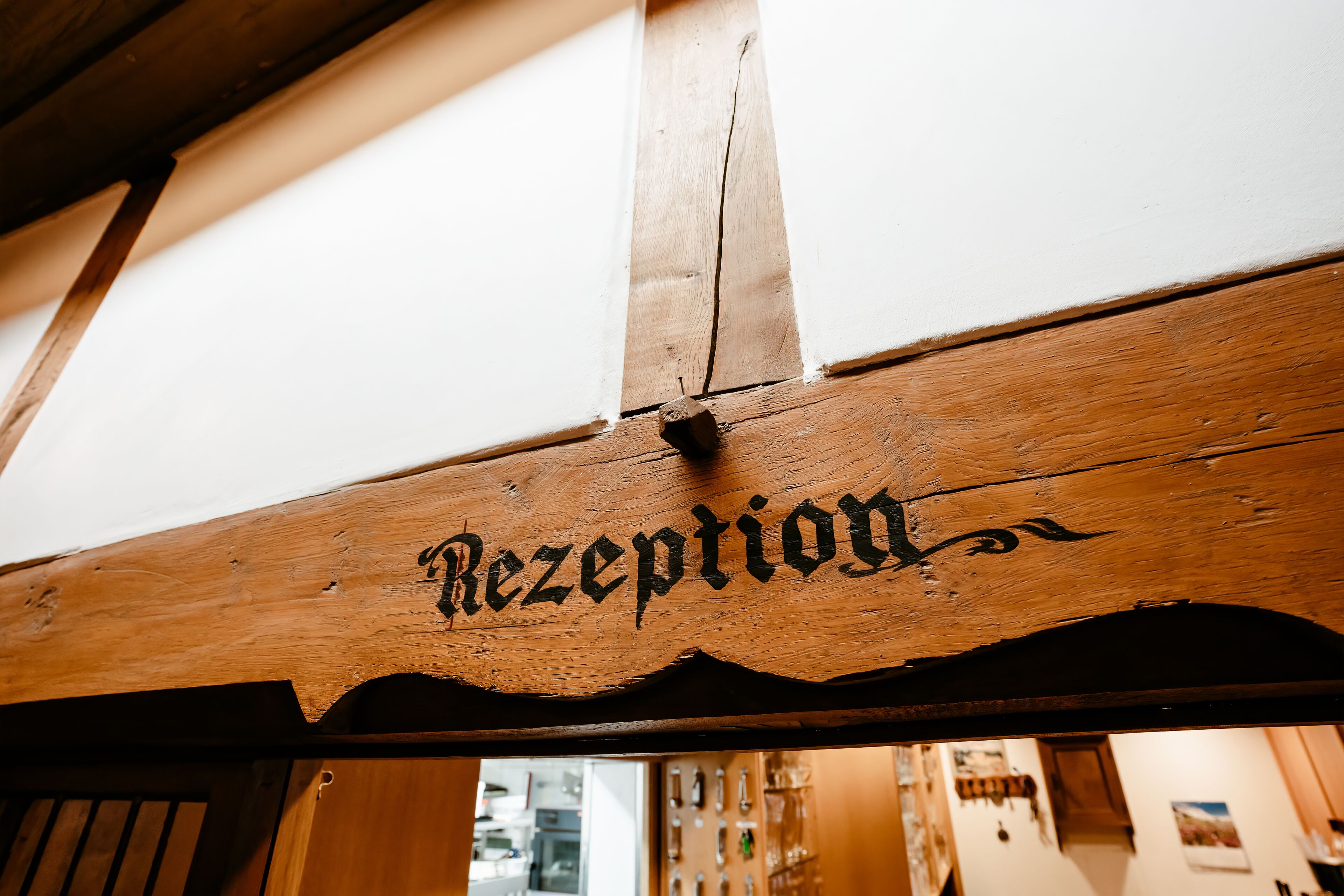 Ein hölzernes Empfangsschild mit der eingravierten Aufschrift 'Rezeption'.