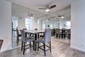 A modern dining area with a glass partition, wooden flooring, and ceiling fans.