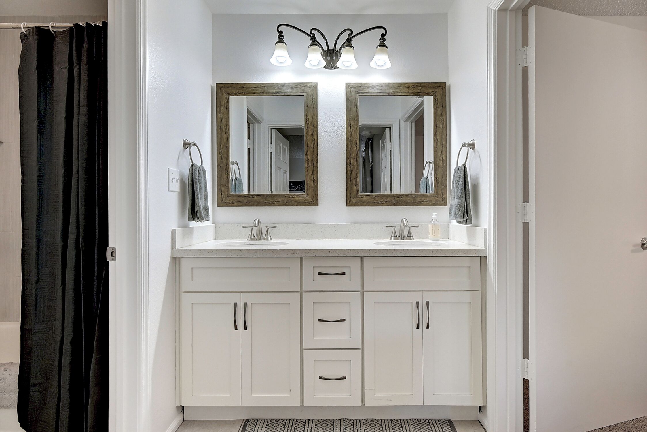 A bathroom with two mirrors, a shower curtain, and a sink with a towel rack.