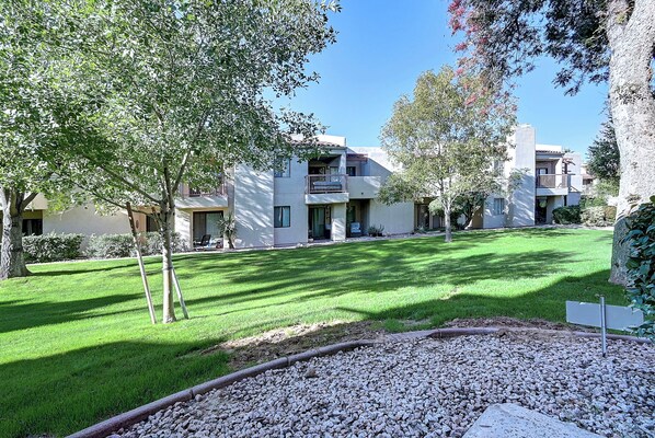 A residential building with multiple balconies, a well-maintained lawn, and a gravel pathway.