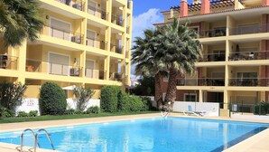Un hotel con piscina, diversi balconi e palme.