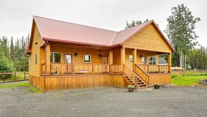 Eine Blockhütte mit rotem Dach, einer Veranda und einer Treppe zum Eingang.