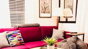 A living room with a red sofa, a round coffee table, and a colorful striped rug.