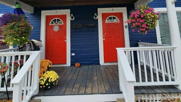 A two-story house with a porch, two red doors, and a blue exterior.