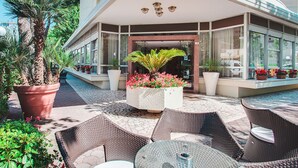 An outdoor seating area with wicker furniture and potted plants. - Hotel Caravelle (Cesenatico)