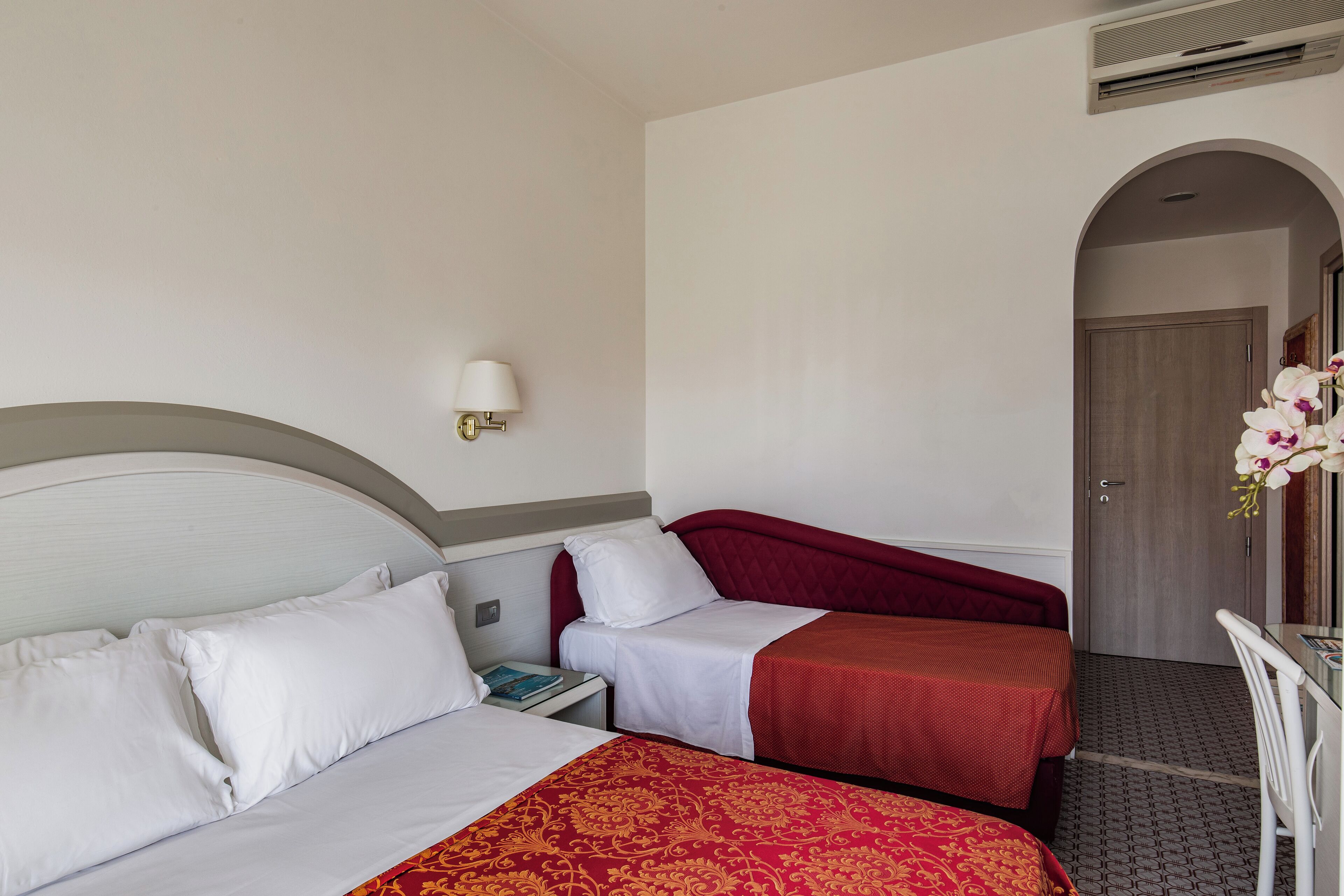 Une chambre d’hôtel avec deux lits, une table de chevet, une lampe et un bureau avec une chaise.