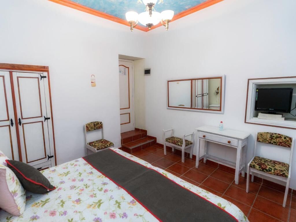 Une chambre à coucher comprenant un lit, un bureau, une chaise, un miroir et un téléviseur.