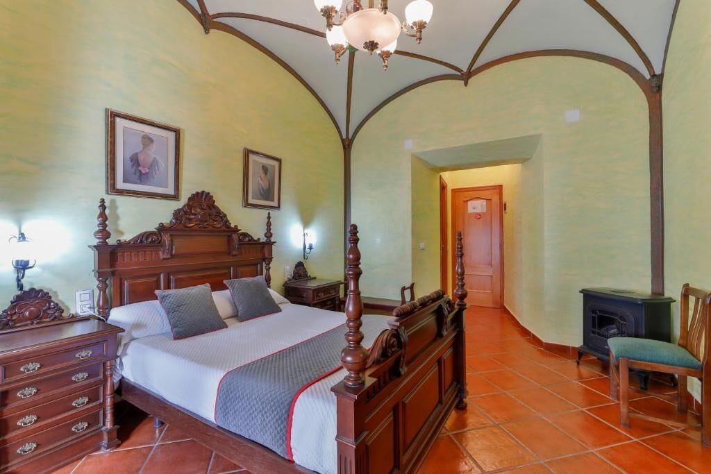 Un dormitorio con cama con dosel, muebles de madera y suelo de baldosas.