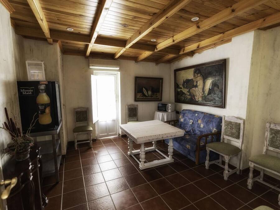 A room with a wooden ceiling, a white table, a blue sofa, and a painting on the wall.