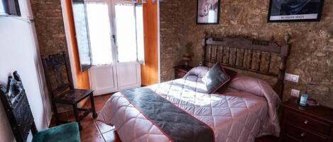 A bedroom with a large bed, a chair, a dresser, and a window with curtains.