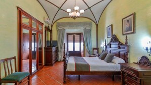 Un dormitorio con cama, muebles de madera, una araña y vistas por la ventana.