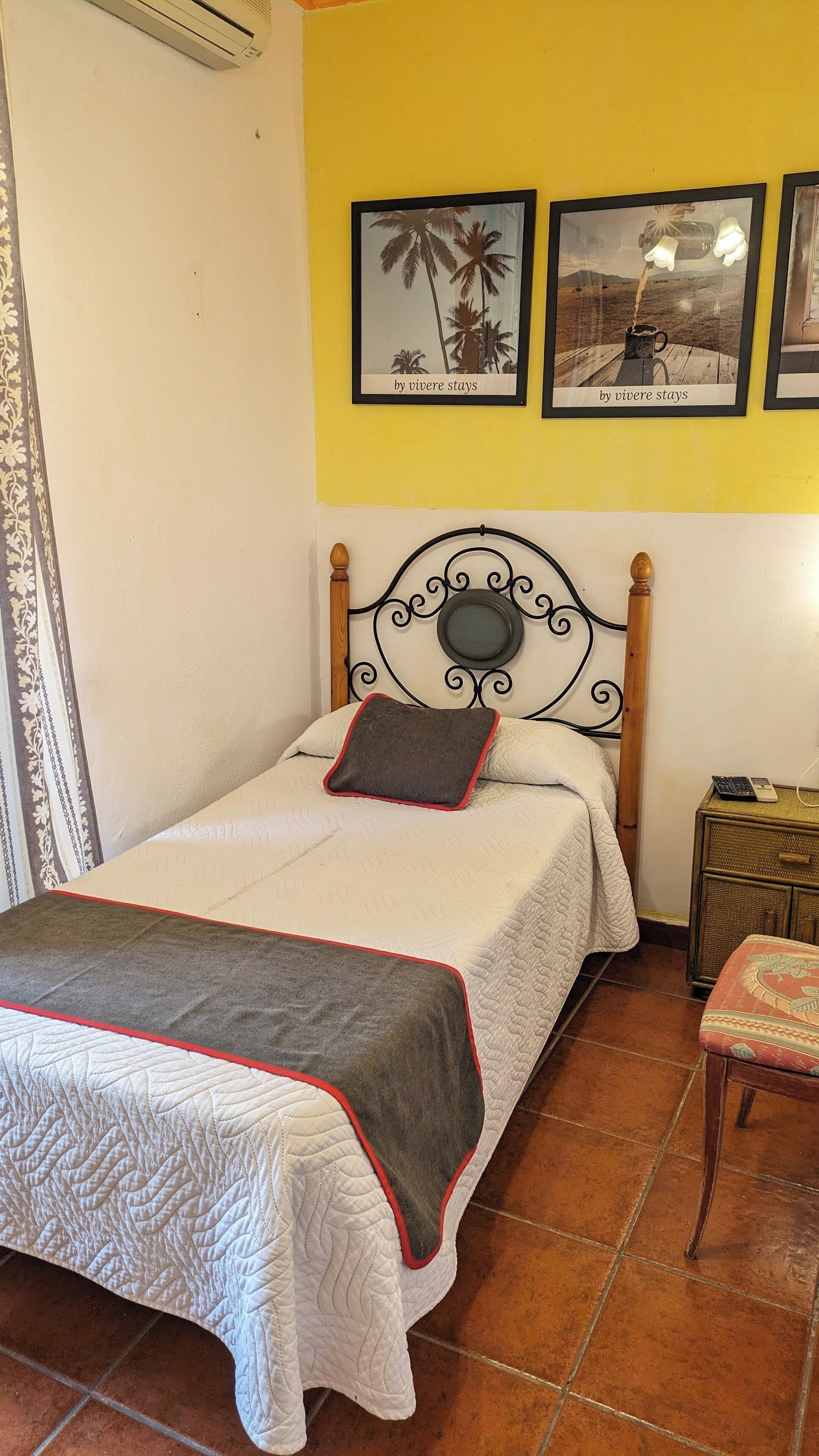 A single bed with a wooden headboard, a bedside table with a lamp, and two framed pictures on the wall.