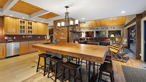 Une cuisine moderne dotée d’un grand îlot central, de tabourets de bar en bois et d’une cheminée en pierre.